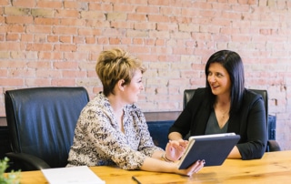 Woman showing another woman something tablet